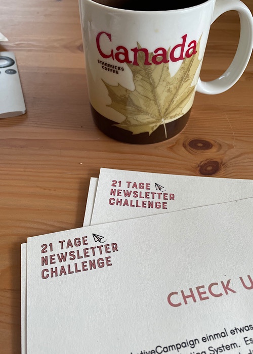 Kaffeetasse mit Canada Schriftzug auf Schreibtisch mit Arbeitsblättern